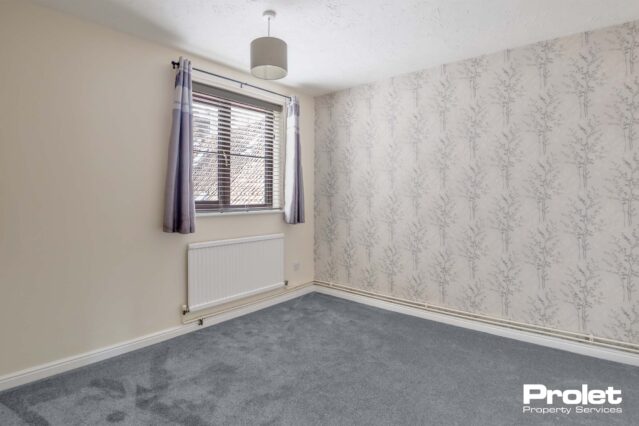 Grey carpets, wallpaper walls and gas central heating with radiator under window