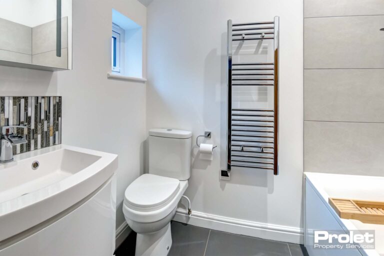 Bathroom with walls painted white and white suite with ladder radiator