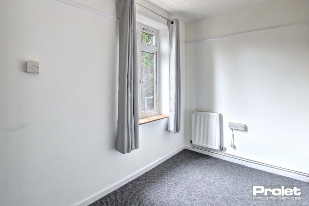 Single bedroom with grey carpets, white walls and large window