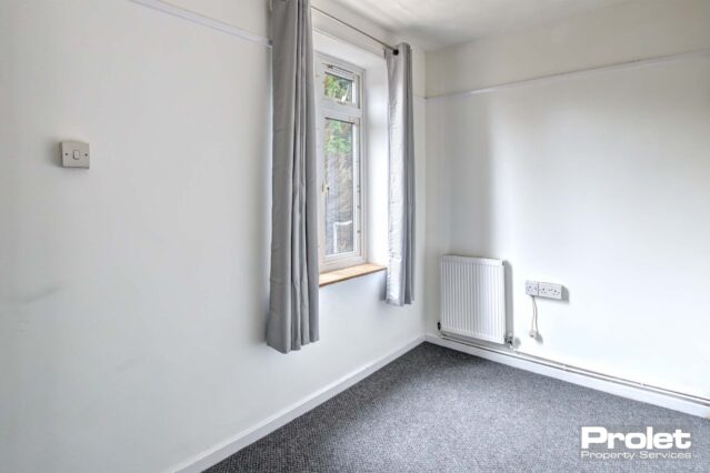Single bedroom with grey carpets, white walls and large window