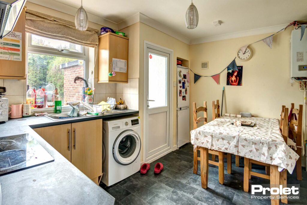 Kitchen with wooden cabinets, washing machine, and wooden dining table and chairs