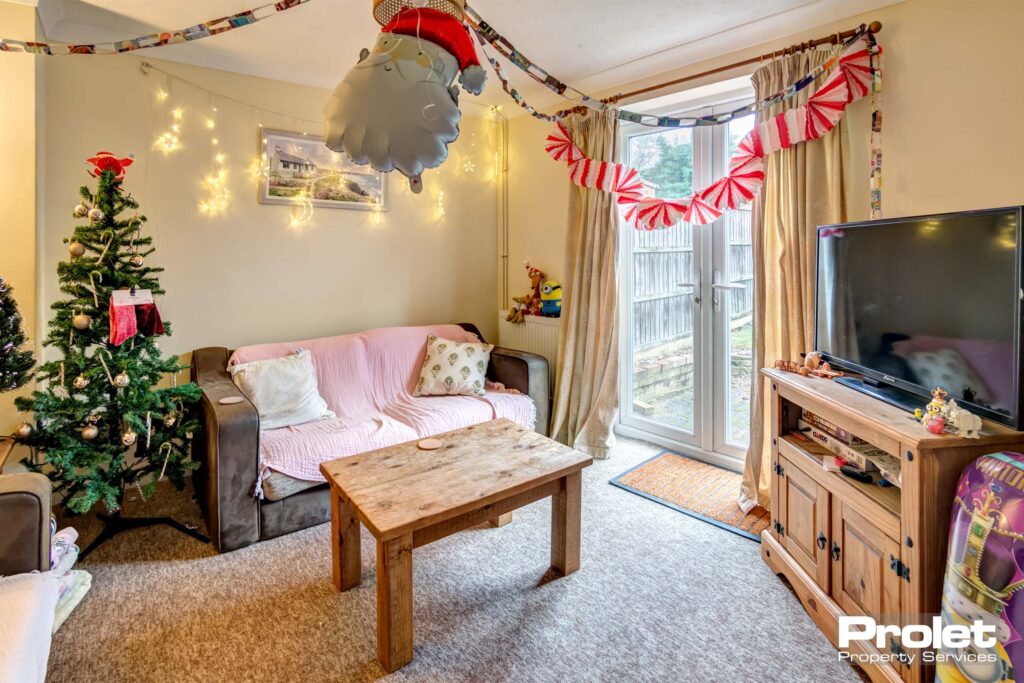 Lounge with grey carpet, sofas, and wooden TV stand