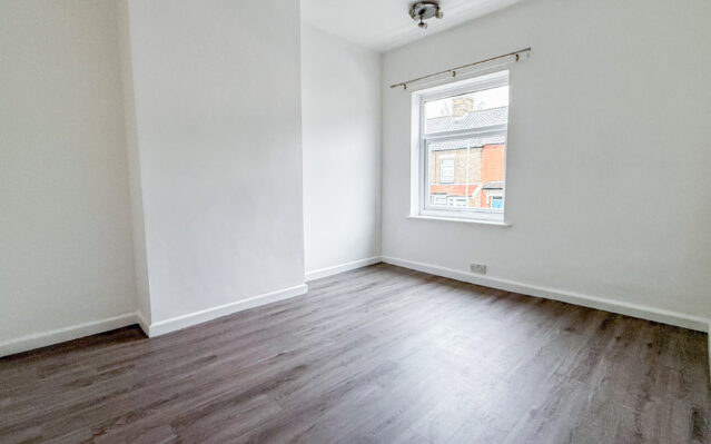 Bedroom with laminate wood effect flooring and white walls