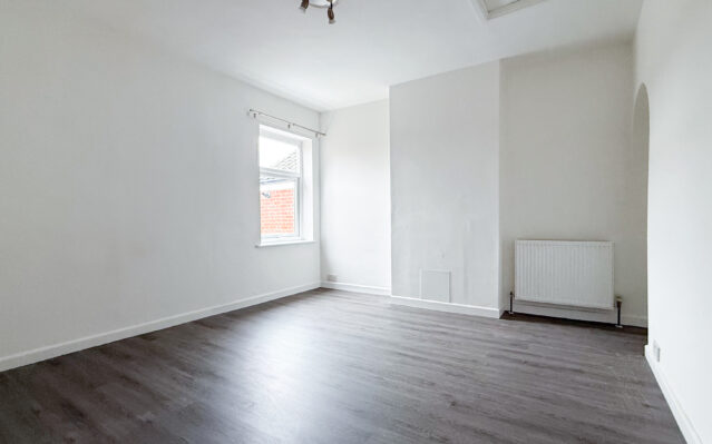 Bedroom with laminate wood effect flooring and white walls