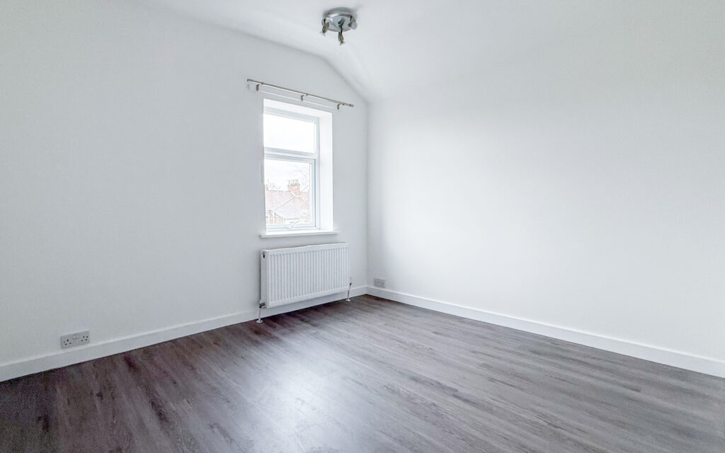 Bedroom with laminate wood effect flooring and white walls