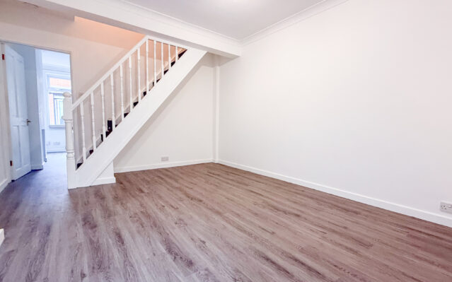 Dining room with laminate wood effect flooring, white walls, and stairs
