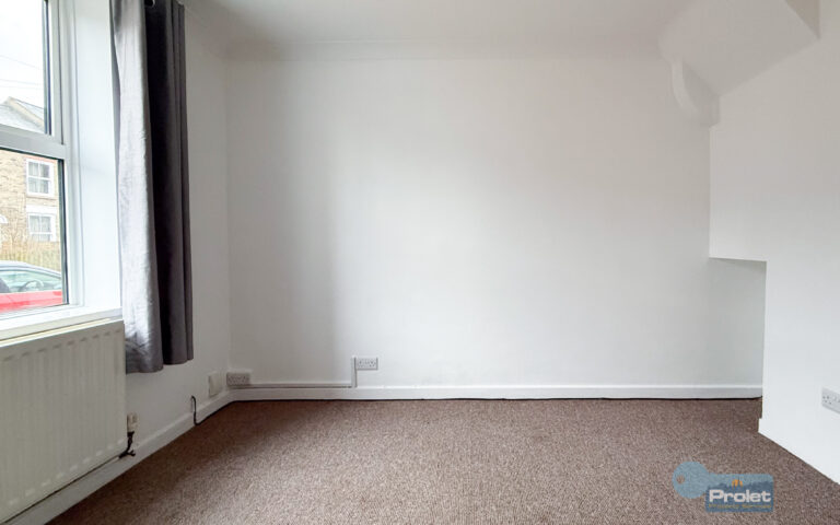 Dining area at front of house, with white walls, and brown carpets.