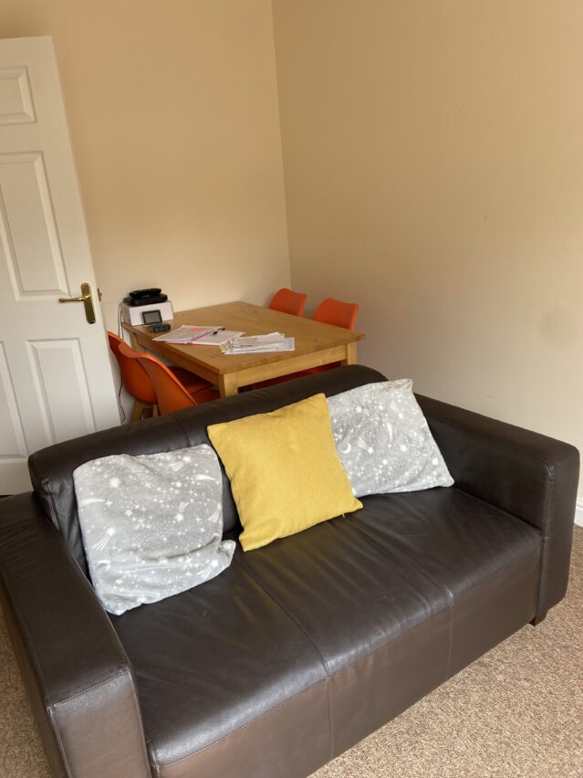 Lounge with brown sofa, and dining table and chairs.