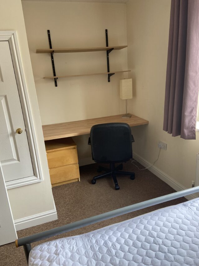 Double bedroom with desk, desk chair, and book shelves