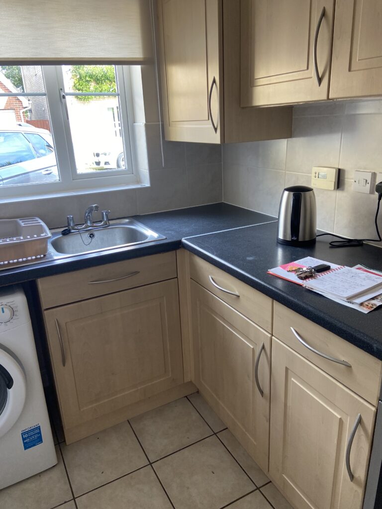 Kitchen with tiled floor, black worktops and wooden cabinets