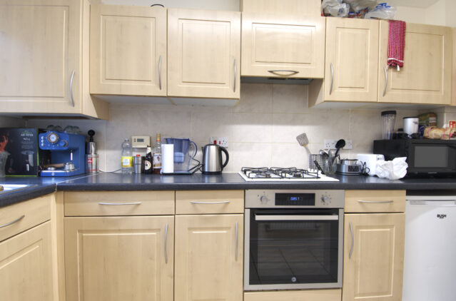 Kitchen with wood cupboards, and black worktop