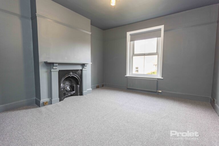 Grey walls and carpet wit feature fireplace large window with venetian blinds