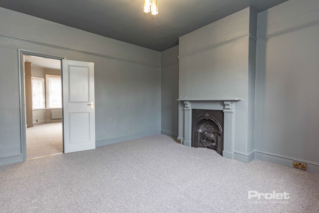 Grey walls and carpet wit feature fireplace large window with venetian blinds