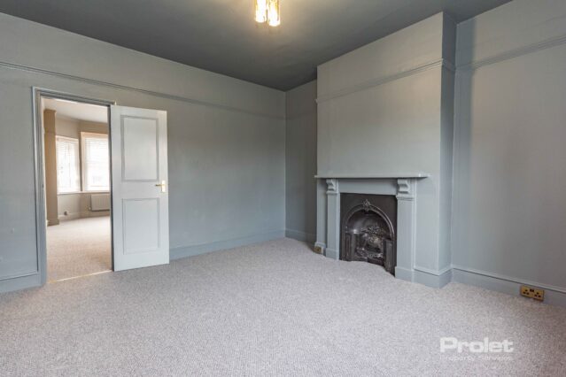 Grey walls and carpet wit feature fireplace large window with venetian blinds