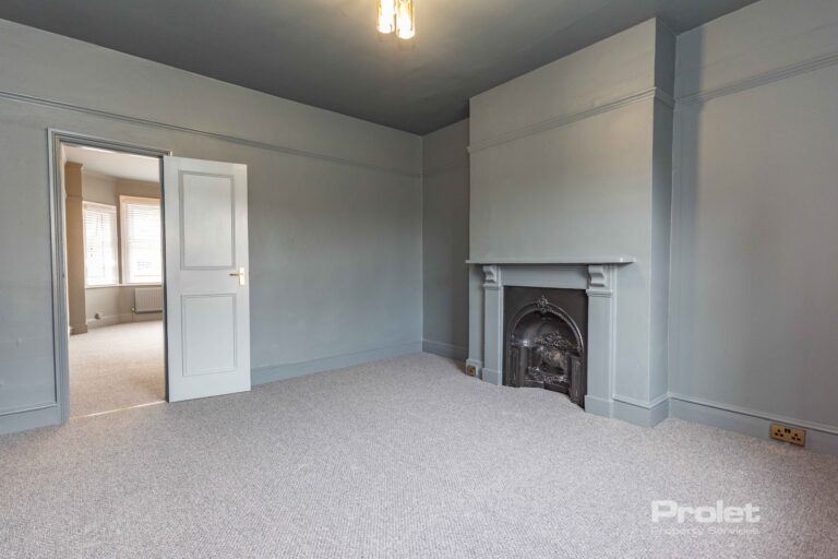 Grey walls and carpet wit feature fireplace large window with venetian blinds