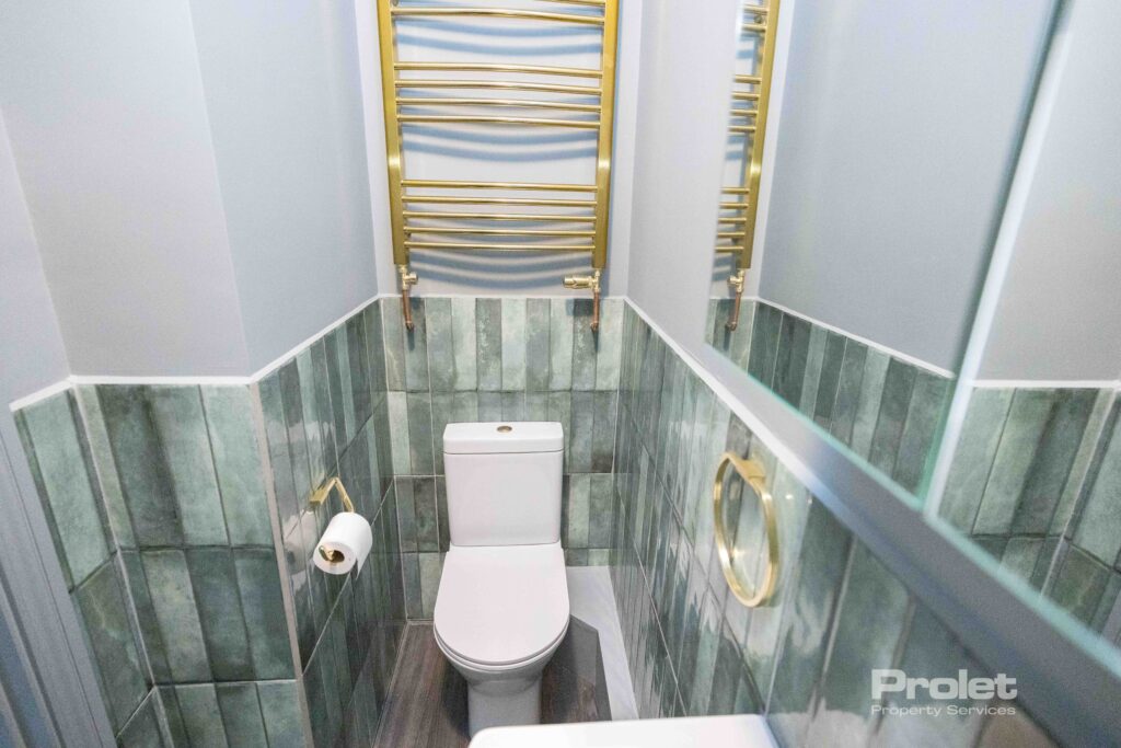 Green wall tiles with white shower suite and brass attachments