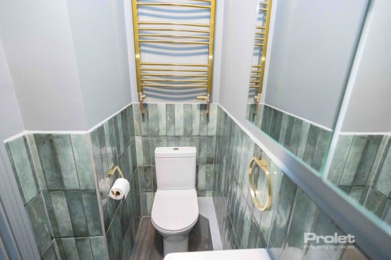 Green wall tiles with white shower suite and brass attachments