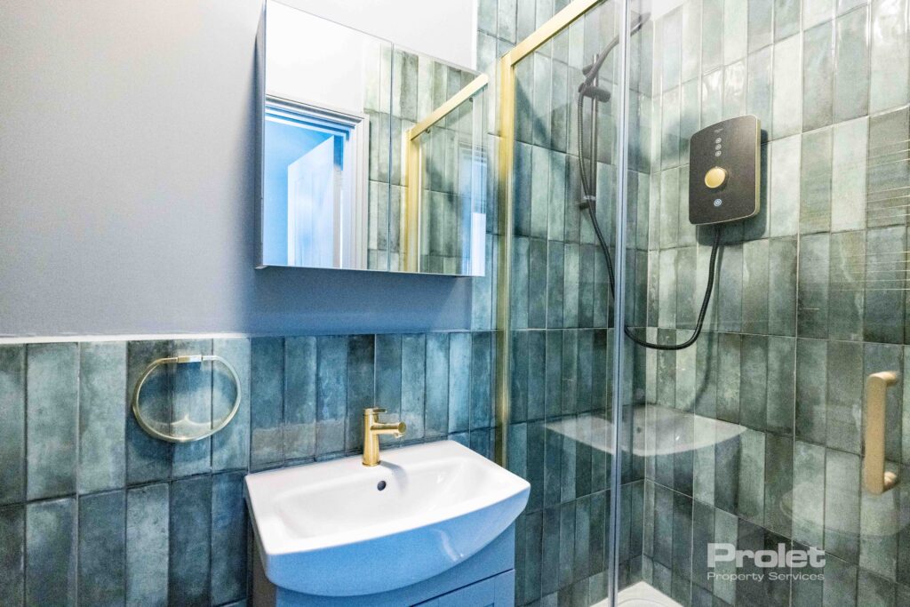 Green wall tiles with white shower suite and brass attachments